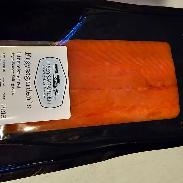 Pakke med røkt ørret fra Frøysagarden, vakuumpakket med svart bakgrunn og tydelig etikett.